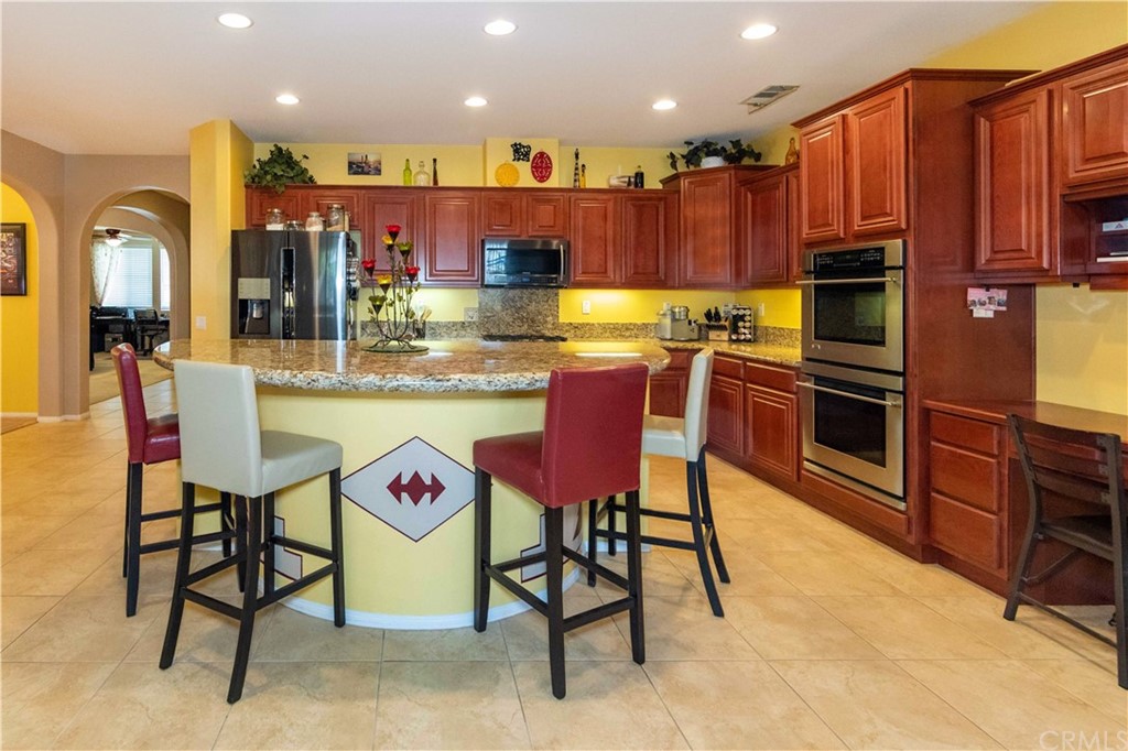 31271 Ensemble Drive Menifee, CA 92584 - Photo 2 of 30 a kitchen with stainless steel appliances kitchen island granite countertop a dining table and chairs