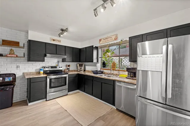 a kitchen with stainless steel appliances granite countertop a refrigerator stove a sink dishwasher and a refrigerator with wooden floor