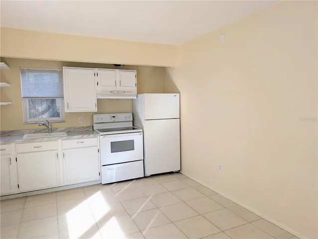 a kitchen with granite countertop white cabinets and white appliances