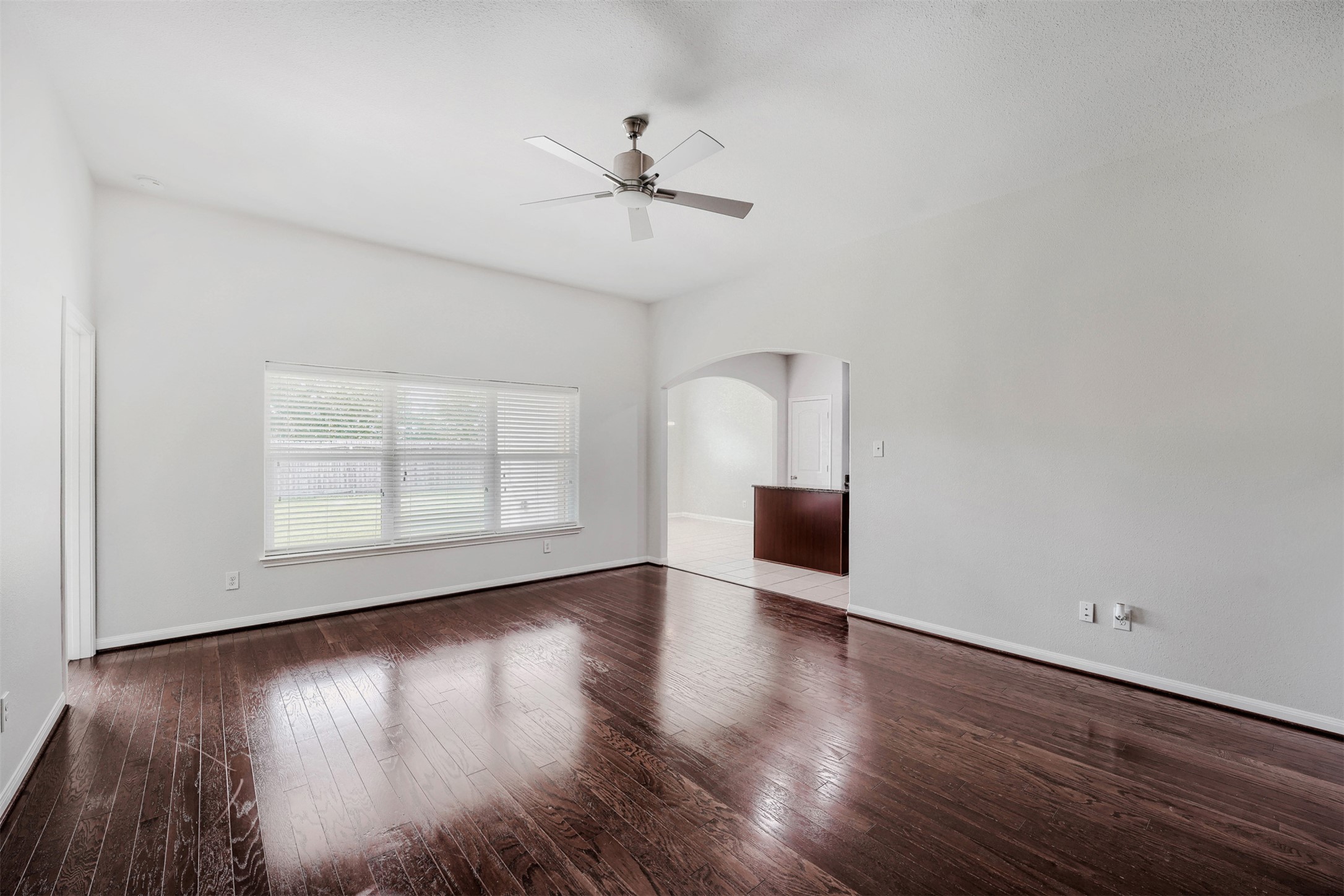 13408 Clara Martin Road Manor, TX 78653 - Photo 11 of 27 an empty room with wooden floor chandelier fan and windows