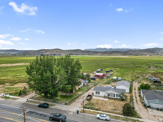 490 South Main Street Kamas, UT 84036 - Photo 22 of 25 White single-story residence with a black shingle roof, front porch, and mature trees