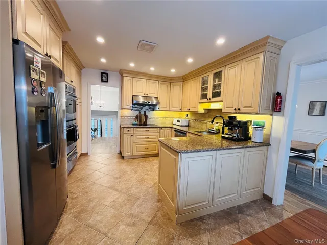 a kitchen with stainless steel appliances kitchen island granite countertop a stove refrigerator and cabinets