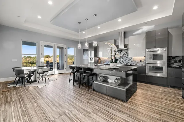 a kitchen with stainless steel appliances granite countertop wooden floors stove and view living room