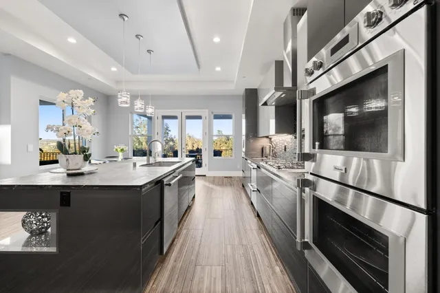 a view of a kitchen with a sink and dishwasher stove a microwave oven with wooden floor