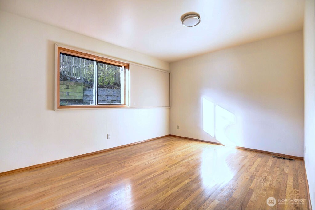 4322 29th Avenue West Seattle, WA 98199 - Photo 19 of 39 an empty room with wooden floor and windows
