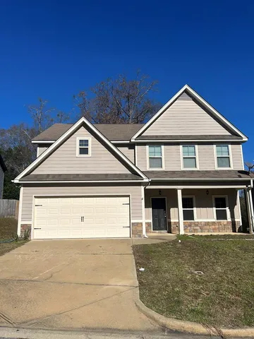 a view of a big house with wooden fence and large trees