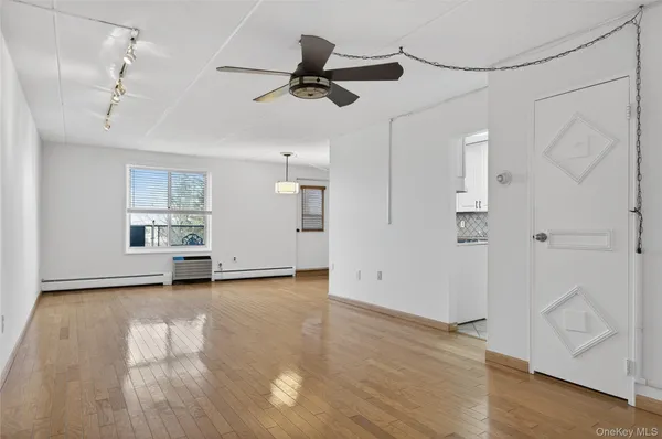 a view of empty room with wooden floor and fan