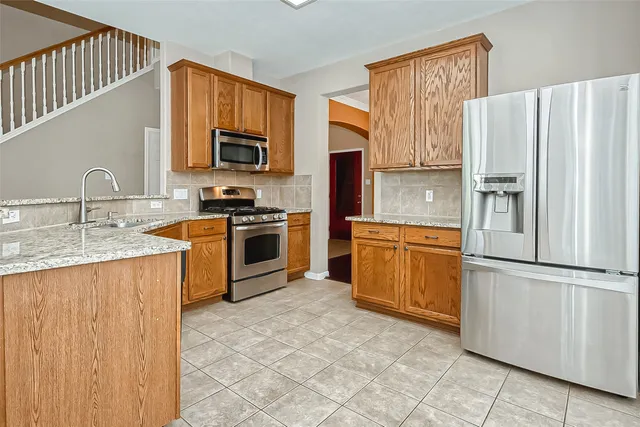 a kitchen with stainless steel appliances granite countertop a refrigerator stove a sink dishwasher and microwave