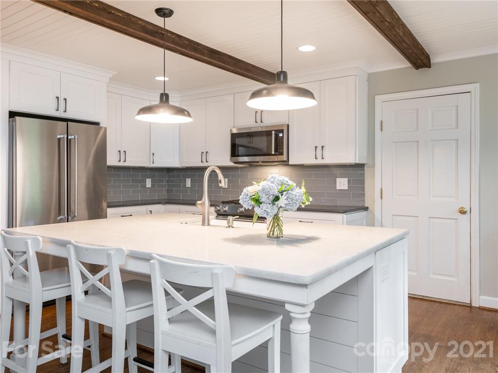 925 Reverdy Lane Matthews, NC 28105 - Photo 10 of 36 a kitchen with kitchen island granite countertop a refrigerator a stove a kitchen island and chairs with wooden floor