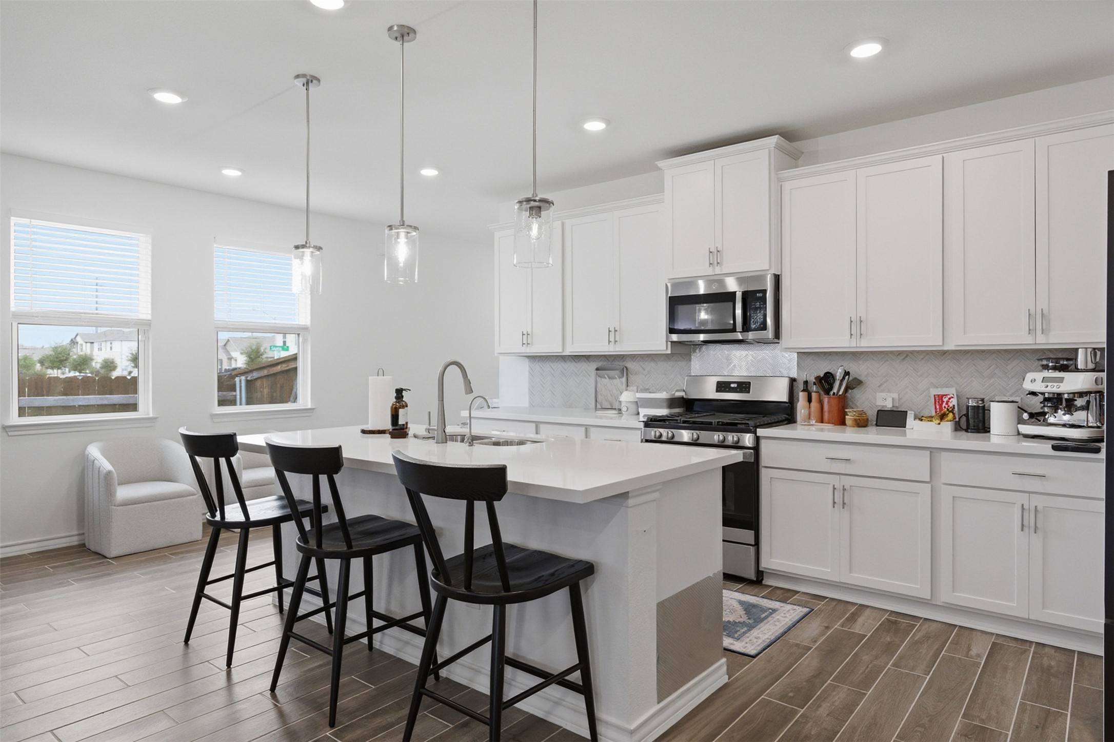 203 Stinchcomb Road Hutto, TX 78634 - Photo 11 of 30 Kitchen featuring stainless steel appliances, white cabinetry, a kitchen bar, and wood finish floors