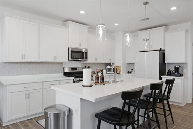 a kitchen with a dining table chairs refrigerator and microwave