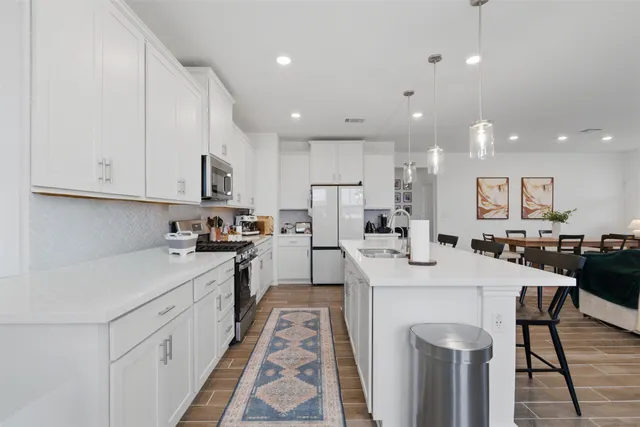 a kitchen with white cabinets sink and stove