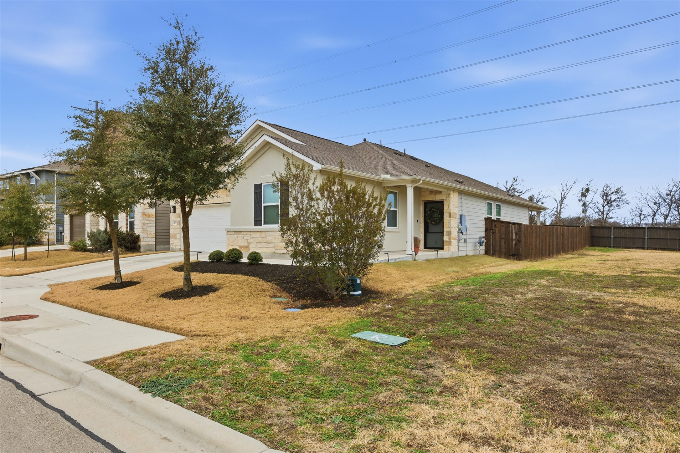 203 Stinchcomb Road Hutto, TX 78634 - Photo 2 of 30 View of front of house with stone siding, concrete driveway, an attached garage, a patio area, and stucco siding
