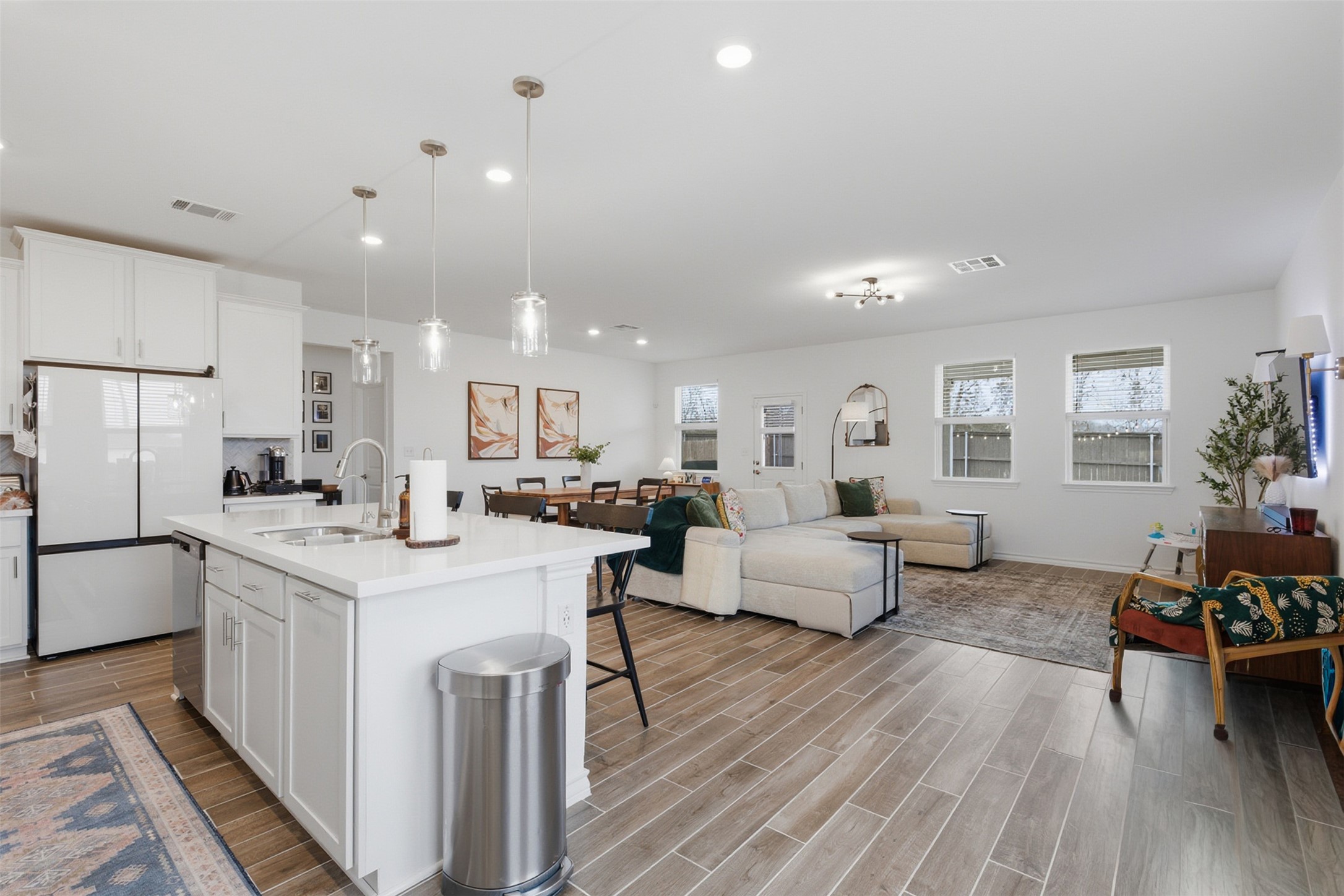 203 Stinchcomb Road Hutto, TX 78634 - Photo 6 of 30 Kitchen featuring white cabinets, wood finish floors, freestanding refrigerator, and decorative light fixtures