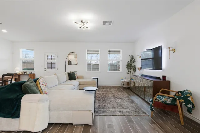 a living room with furniture a flat screen tv and a window
