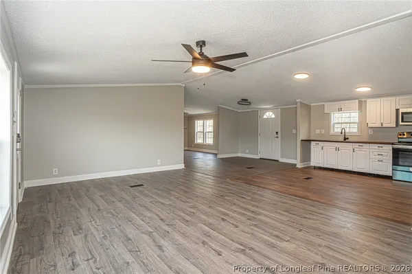 a view of an empty room with wooden floor and a ceiling fan
