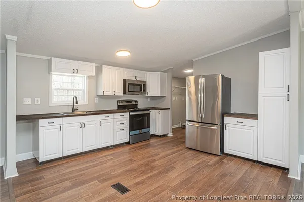 a kitchen with granite countertop a refrigerator and wooden floors