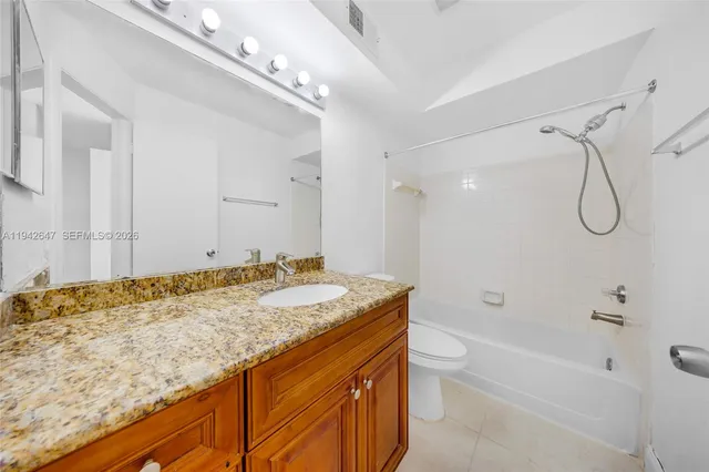 a bathroom with a granite countertop sink a toilet and shower