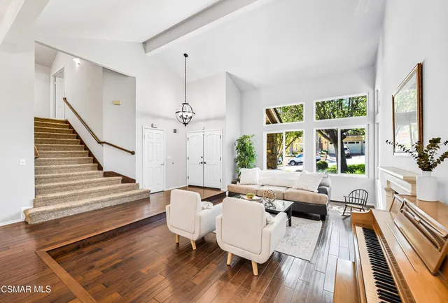 a living room with furniture floor to ceiling window and wooden floor