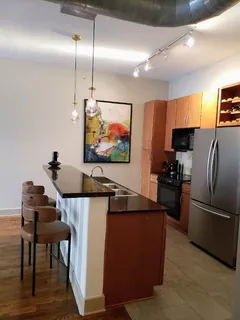 a kitchen with stainless steel appliances kitchen island granite countertop a table chairs sink and microwave