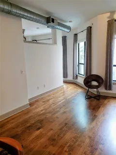 a view of a room with wooden floor a mirror and windows