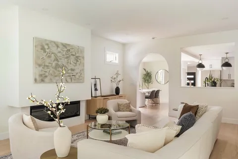 a living room with furniture flowers and a large mirror