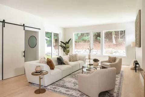 a living room with furniture a large window and a chandelier