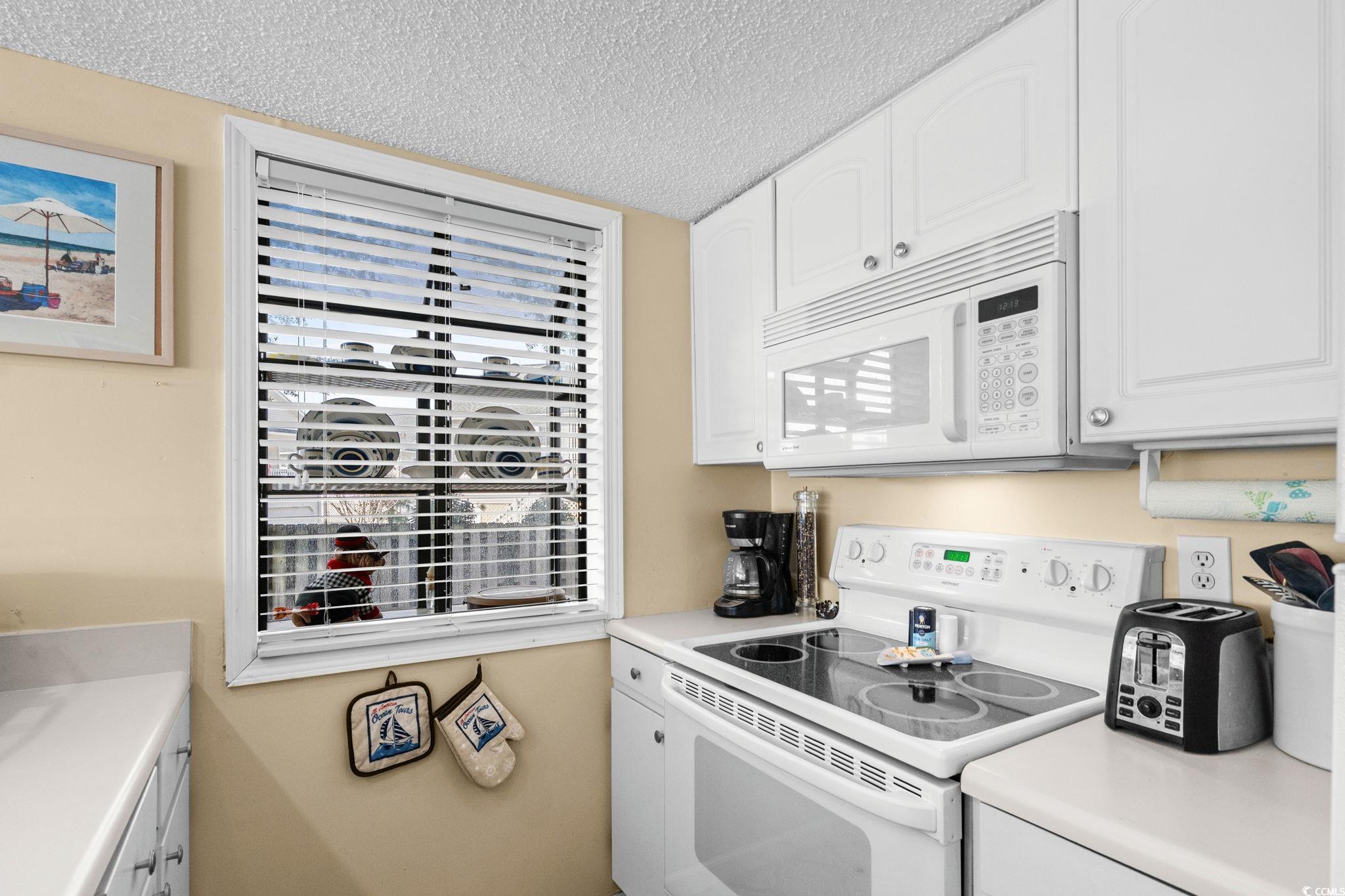 351 Lake Arrowhead Road, Unit 20179 Myrtle Beach, SC 29572 - Photo 14 of 40 Kitchen with white appliances, white cabinets, and a textured ceiling