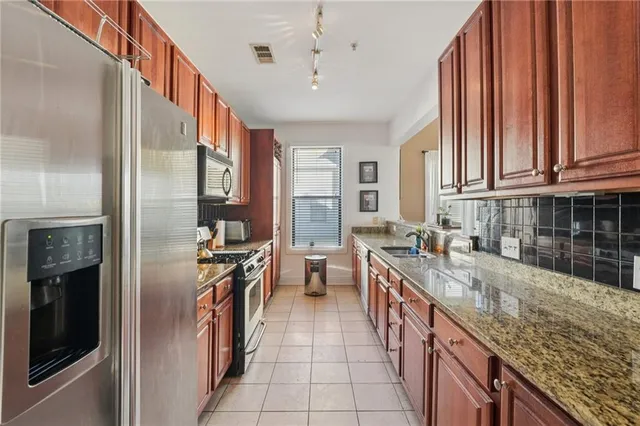 a kitchen with stainless steel appliances granite countertop a stove a sink and a refrigerator