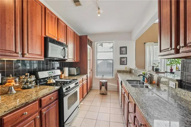 a kitchen with stainless steel appliances granite countertop a stove a sink and a microwave