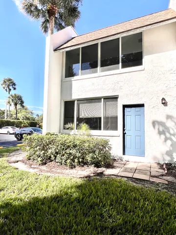 a view of a house with a big yard and palm trees