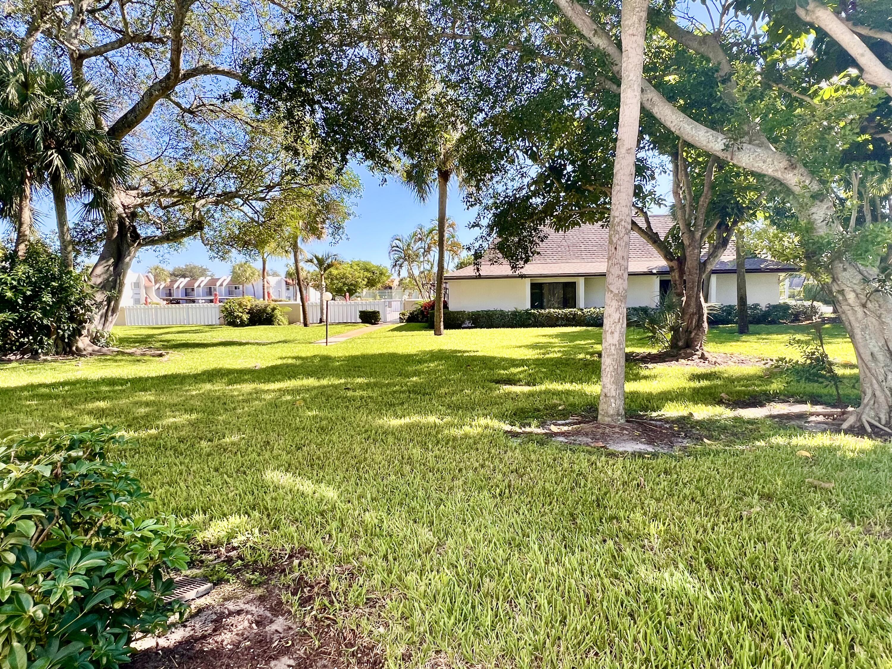 2865 Southwest 22nd Avenue, Unit 108 Delray Beach, FL 33445 - Photo 15 of 16 a view of a house with a big yard and palm trees