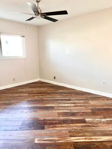 an empty room with wooden floor closet and fan