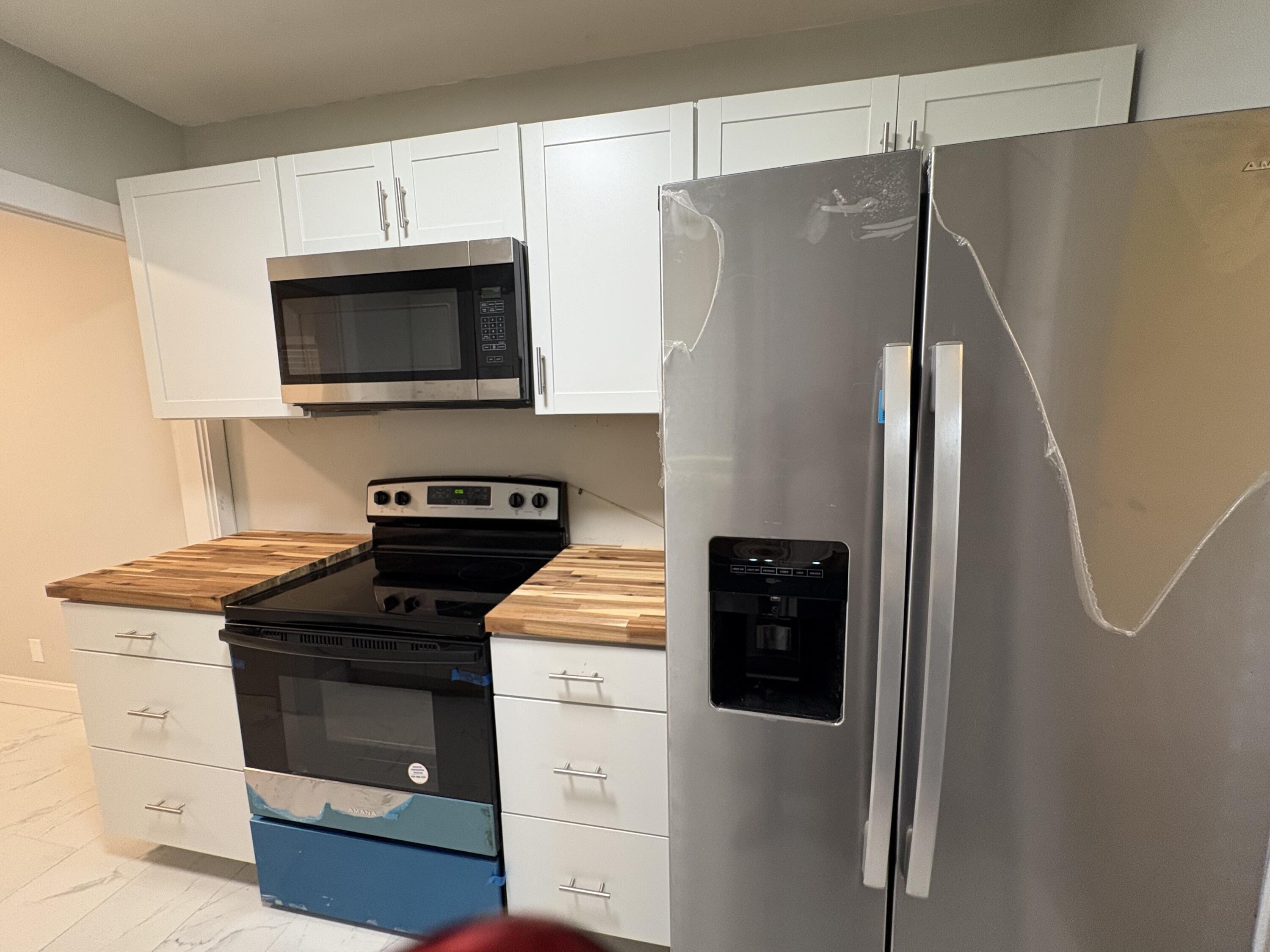 1010 Mayflower Road Fort Pierce, FL 34950 - Photo 7 of 27 a kitchen with stainless steel appliances a refrigerator stove and microwave