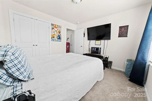 a bedroom with a bed a flat tv screen and a lamp on the dresser