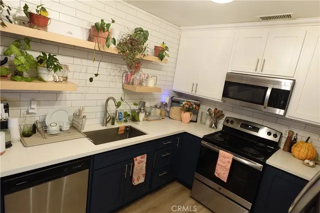 a kitchen with stainless steel appliances a sink dishwasher stove and refrigerator