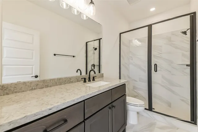 a bathroom with a granite countertop sink a toilet and shower