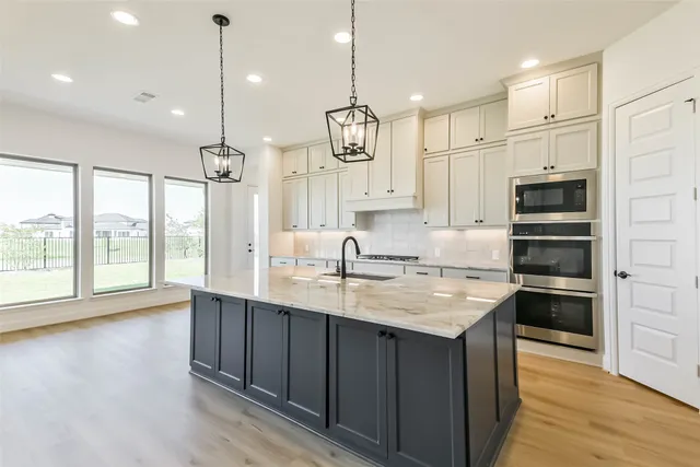 a kitchen with kitchen island granite countertop a sink appliances and wooden floor
