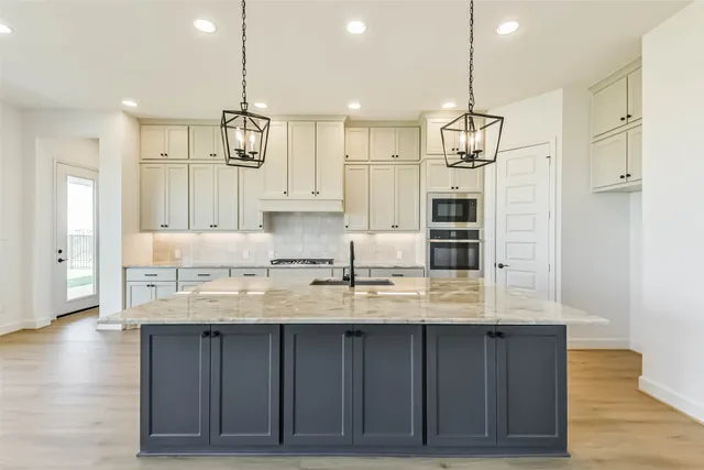 a kitchen with kitchen island granite countertop a sink cabinets and stainless steel appliances