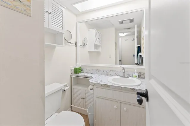 a bathroom with a granite countertop toilet sink and mirror