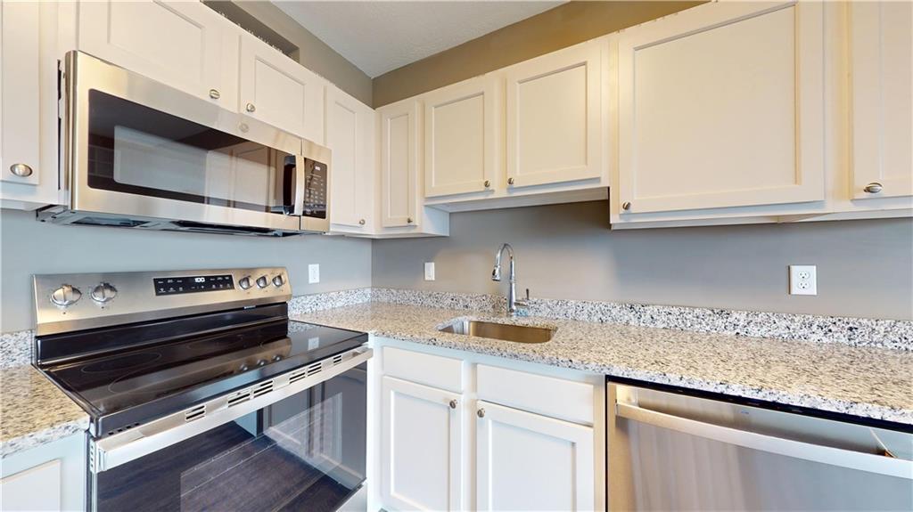 1450 Fifth Avenue, Unit 202 Pittsburgh, PA 15219 - Photo 17 of 20 a kitchen with stainless steel appliances granite countertop a sink a stove and microwave