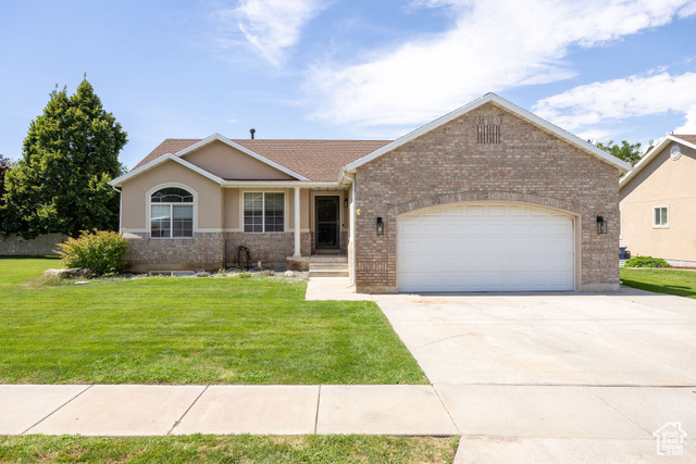 2280 South 450 West Perry, UT 84302 - Photo 2 of 38 View of front of house featuring a front yard, concrete driveway, an attached garage, and stucco siding