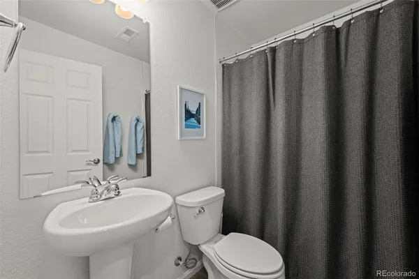 a bathroom with a sink a toilet a mirror and shower curtain