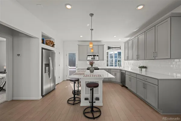 a kitchen with kitchen island a dining table chairs stainless steel appliances and cabinets