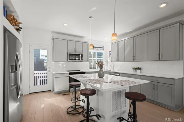 a kitchen with stainless steel appliances kitchen island granite countertop a sink a stove a refrigerator and cabinets