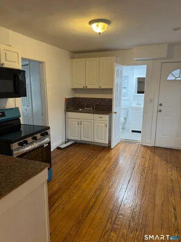 a kitchen with granite countertop a stove and a wooden floors