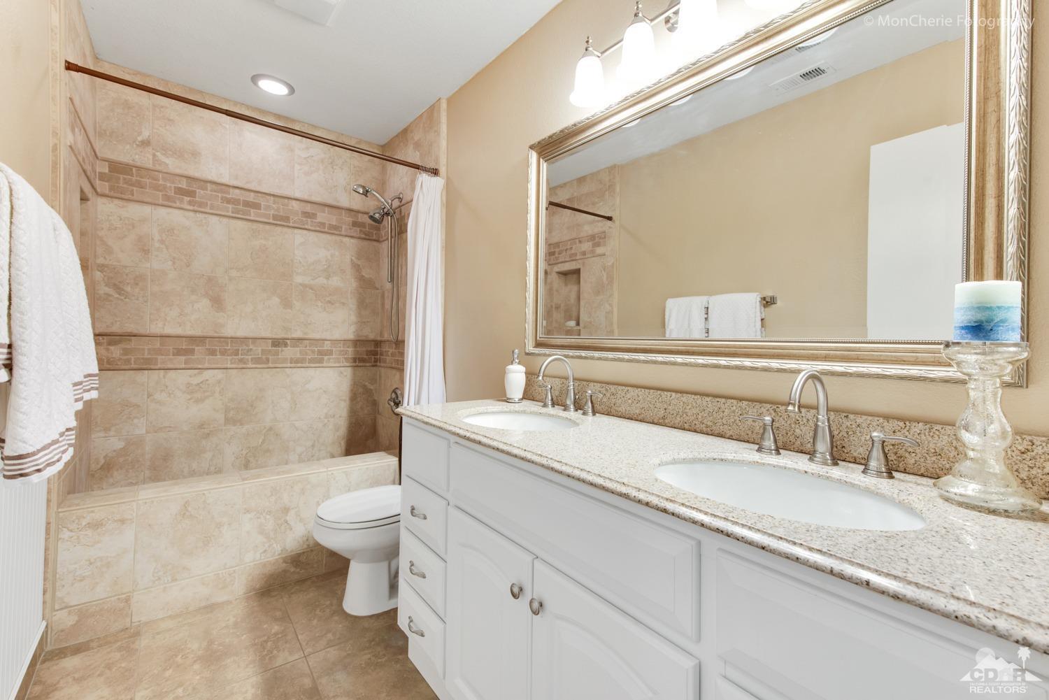 41675 Front Hall Road Bermuda Dunes, CA 92203 - Photo 18 of 23 a bathroom with a granite countertop sink a toilet a mirror and shower