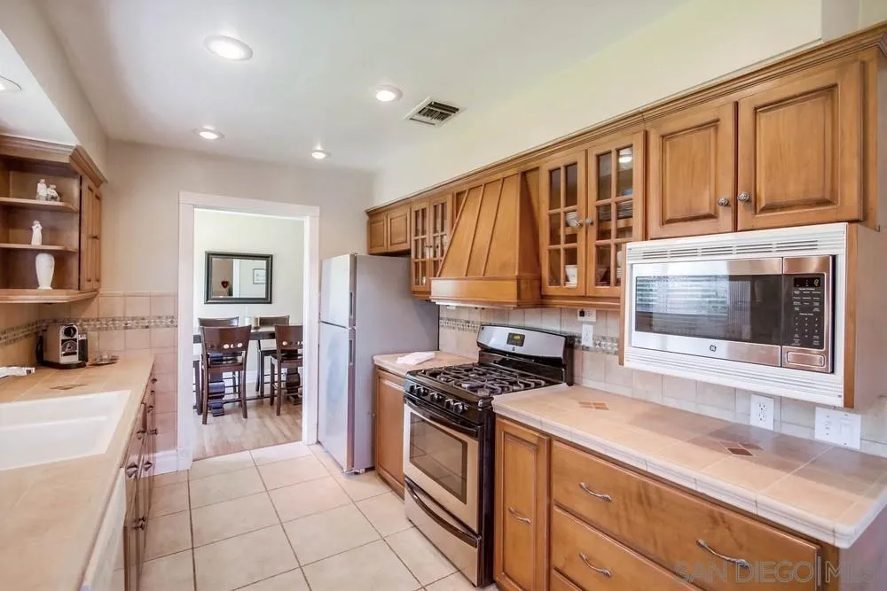 14655 Evening Star Drive Poway, CA 92064 - Photo 19 of 33 a kitchen with granite countertop a stove top oven a sink a dining table and chairs