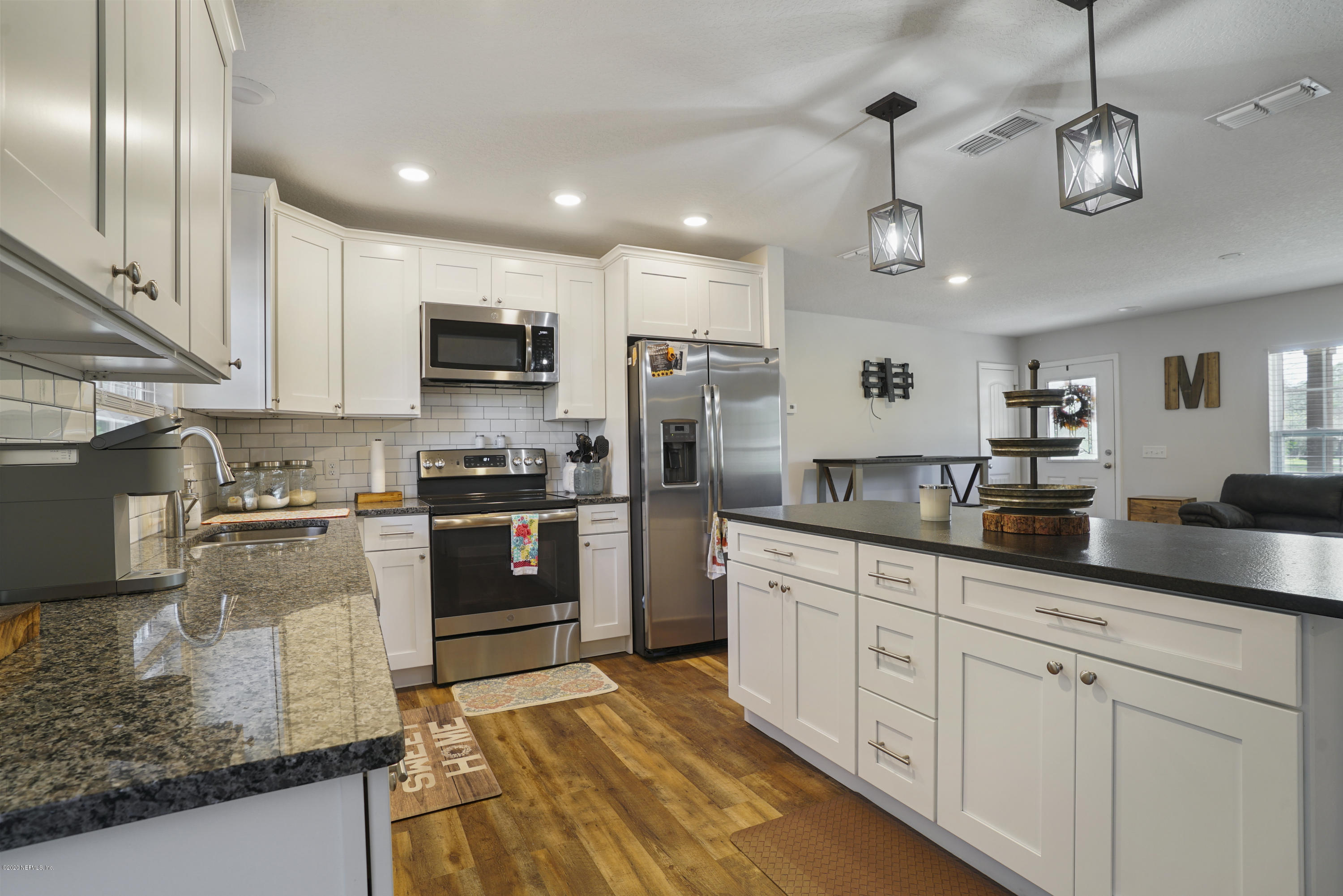 54096 Jeannie Road Callahan, FL 32011 - Photo 7 of 19 a kitchen with granite countertop stainless steel appliances cabinets a sink and a counter top space