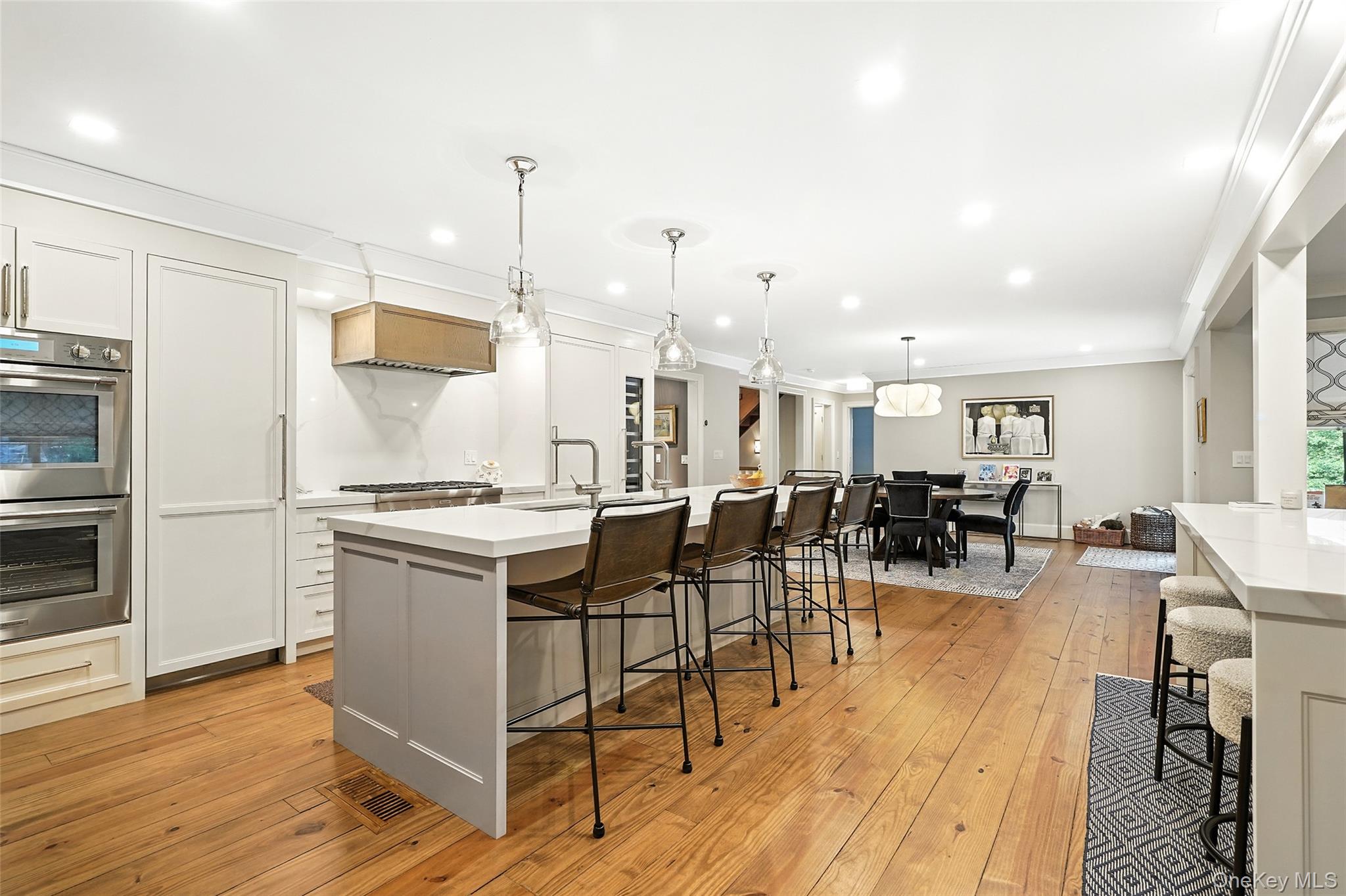 548 Anderson Hill Road Purchase, NY 10577 - Photo 15 of 46 a view of a kitchen with kitchen island a stove a refrigerator a dining table and chairs with wooden floor